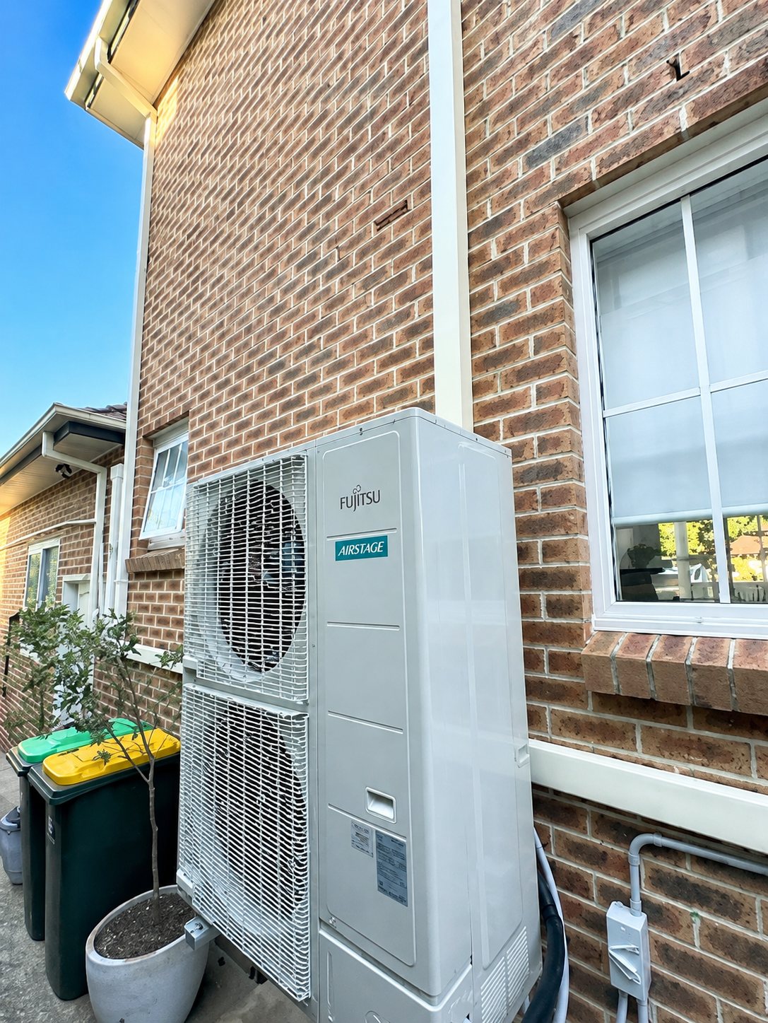Fujitsu Airstage ducted condenser installed beside a brick home